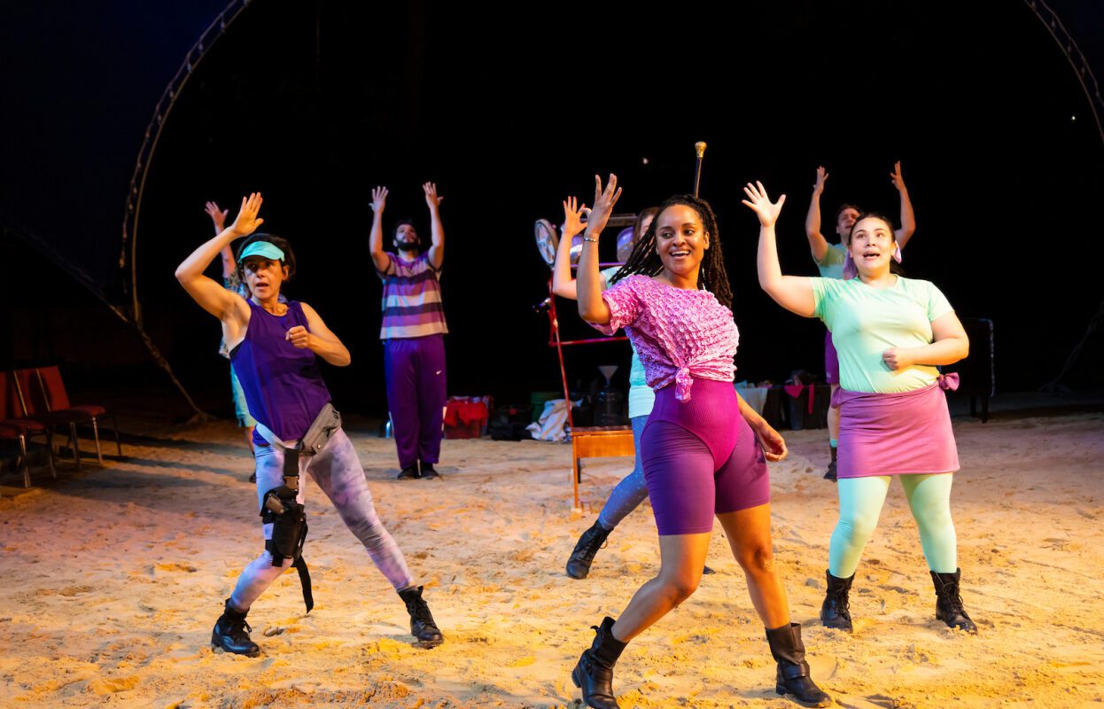 three women in 80s style workout gear dance and sweat in unison with backup dancers at the hudson valley shakespeare festival